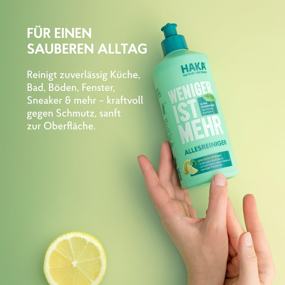 Hand hält Allesreiniger 475ml Flasche daneben liegt eine Zitronenscheibe